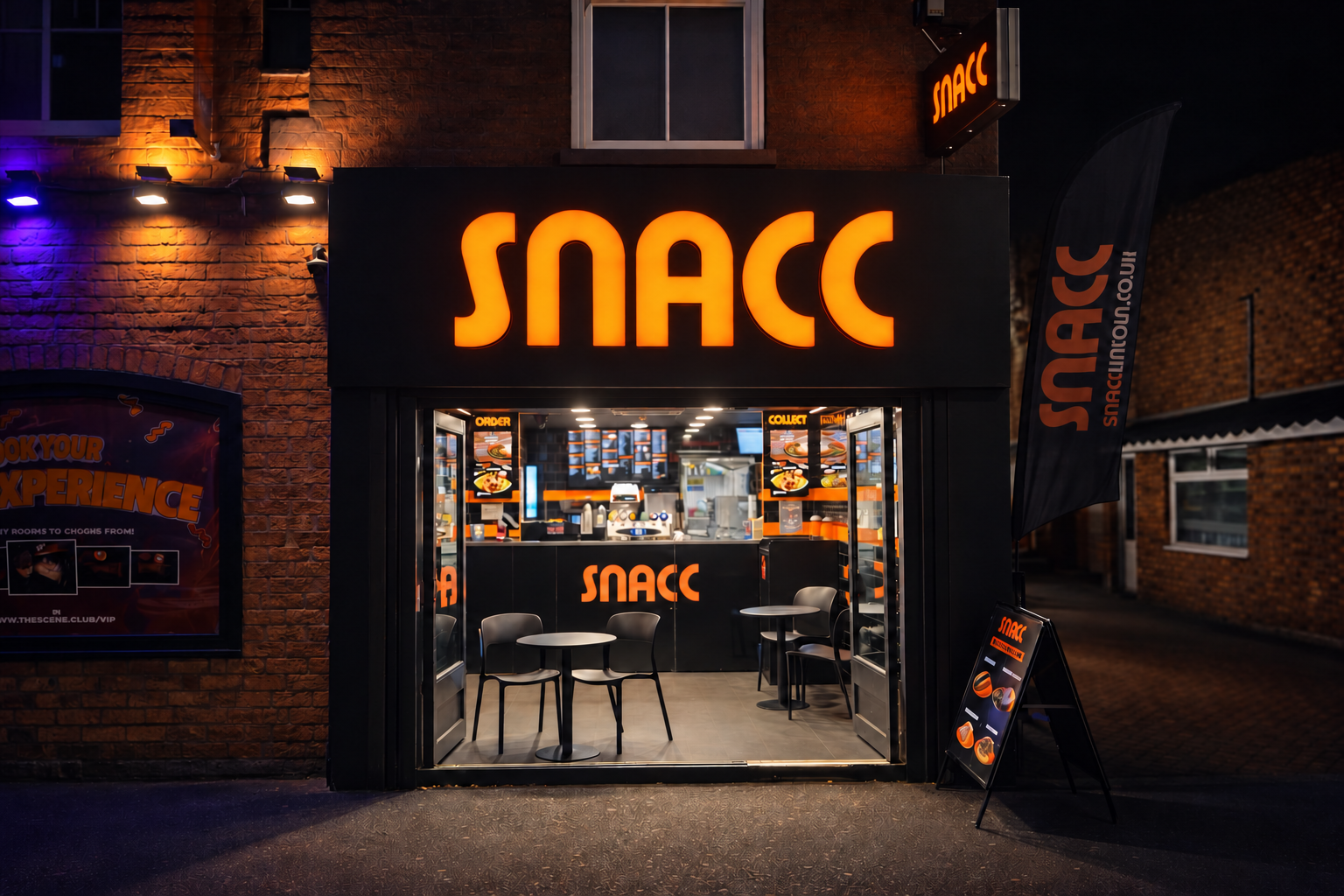 Snacc Lincoln shopfront at night, with the orange sign and seating visible inside